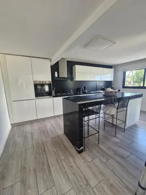 a large kitchen with a black counter top and wooden floors at Casa con hermosa vista al lago in Villa Carlos Paz