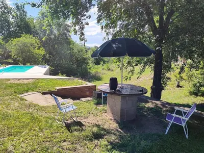 a stone table with an umbrella and two chairs at Cabana Cecilia in Villa Icho Cruz