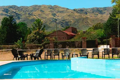 a swimming pool with chairs and mountains in the background at Ayres del Bosque in Merlo
