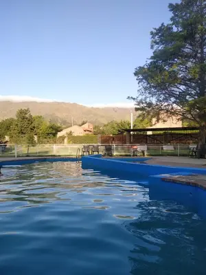 a pool of blue water with a tree in the background at Ayres del Bosque in Merlo