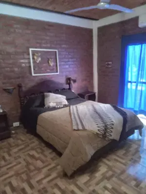 a bedroom with a large bed with a brick wall at Lo de iaia in Carpintería