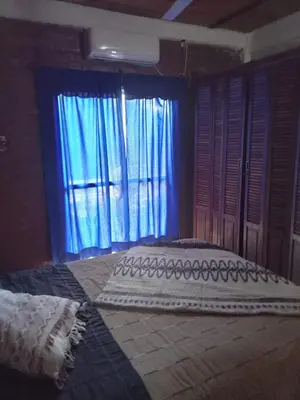 a bedroom with a large window with blue curtains at Lo de iaia in Carpintería
