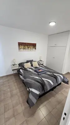 a large bed in a white room with two tables at Dpto zona NUEVO CENTRO shopping y PATIO OLMOS in Cordoba
