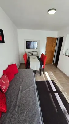 a living room with a bed and a table with red pillows at Dpto zona NUEVO CENTRO shopping y PATIO OLMOS in Cordoba