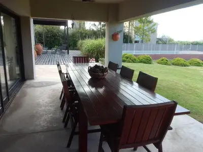 a wooden table and chairs on a patio at Sobre lago Los Molinos in Villa Anizacate