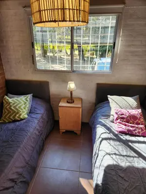 a room with two beds and a table with a lamp at Rio Sereno in Santa Rosa de Calamuchita