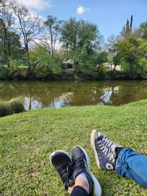 a person sitting on the grass next to a river at Rio Sereno in Santa Rosa de Calamuchita