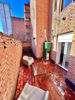 a patio with a brick wall and a table and chairs at Refugio urbano frente a Sanatorio Allende in Cordoba