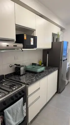 a kitchen with white cabinets and a stove top oven at Dpto con vista a las sierras in Cordoba