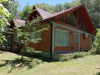 a small brick house with a tree in front of it at Chalet del arroyo in La Porteña