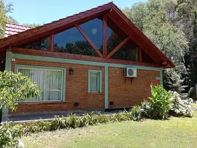 a small brick house with a large window at Chalet del arroyo in La Porteña