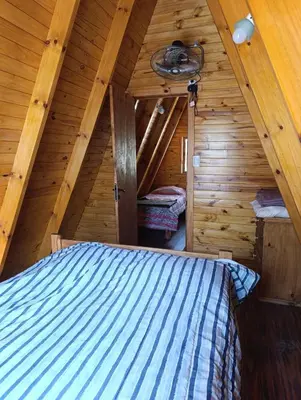 a bedroom in a log cabin with a bed at Alpinas Aliwé in San Ignacio