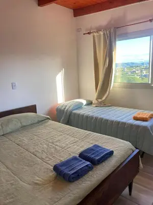 two beds in a room with a window at Departamento ideal Pileta, Parrilla y Pet friendly in Cavalango