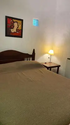 a bedroom with a bed and a table with a lamp at Cabañas Mate de Luna in Santa Rosa de Calamuchita