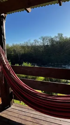 a hammock on a deck with a view of the water at Cabañas Mate de Luna in Santa Rosa de Calamuchita