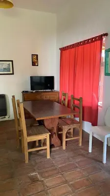 a dining room with a wooden table and a red curtain at Cabañas Mate de Luna in Santa Rosa de Calamuchita