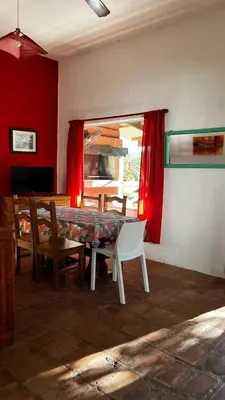 a dining room with a table and red curtains at Cabañas Mate de Luna in Santa Rosa de Calamuchita
