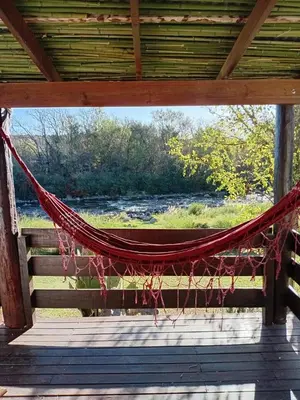a hammock on a porch with a view of a river at Cabañas Mate de Luna in Santa Rosa de Calamuchita