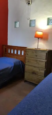 a bedroom with a bed and a dresser with a lamp at Cabañas Mate de Luna in Santa Rosa de Calamuchita