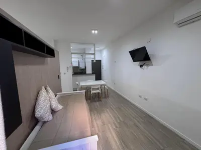 a white room with a table and a tv on the wall at Girolami Temporarios Villa Carlos Paz in Villa Carlos Paz