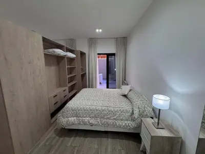 a bedroom with a bed and a table and a lamp at Girolami Temporarios Villa Carlos Paz in Villa Carlos Paz