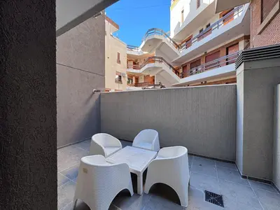 a balcony with two chairs and a table and a building at Girolami Temporarios Villa Carlos Paz in Villa Carlos Paz