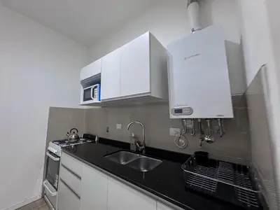 a kitchen with white cabinets and a sink at Girolami Temporarios Villa Carlos Paz in Villa Carlos Paz