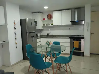 a kitchen with a glass table and blue chairs at NGdeptosVCP in Villa Carlos Paz