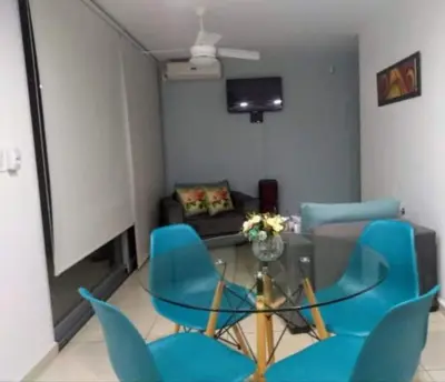 a living room with a glass table and blue chairs at NGdeptosVCP in Villa Carlos Paz