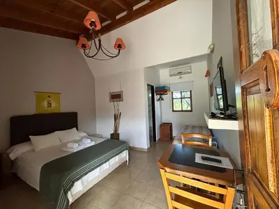 a bedroom with a bed and a desk with a television at Hosteria Manantial de Carpintería in Carpintería