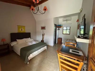 a bedroom with a bed and a desk and a television at Hosteria Manantial de Carpintería in Carpintería