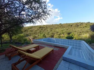 a swimming pool with a chaise lounge and a table and chairs at Casa familiar de Campo Arev in Las Rabonas