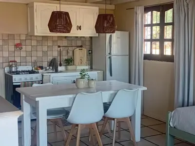 a kitchen with a white table and white chairs at Casitas de Campo in Mina Clavero
