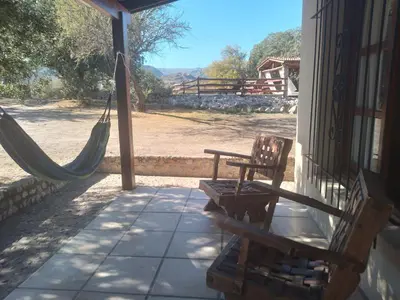 a porch with two chairs and a hammock on a house at Casitas de Campo in Mina Clavero