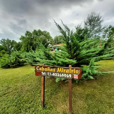 a sign in front of a palm tree at Miralrio in Santa Rosa de Calamuchita