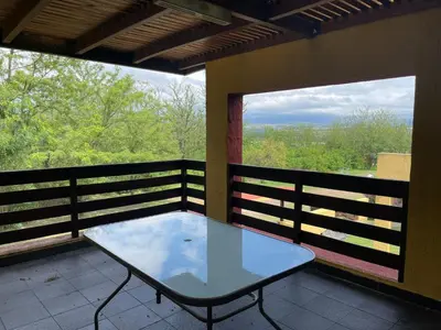 a glass table on a balcony with two windows at Depto a 10 min de Villa General Belgrano in Villa Ciudad Parque