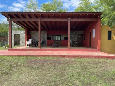 a pavilion with tables and chairs in a building at Depto a 10 min de Villa General Belgrano in Villa Ciudad Parque