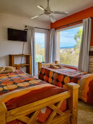 a bedroom with two beds and a large window at Cabañas Quebrada del Lobito in Villa Santa Cruz del Lago