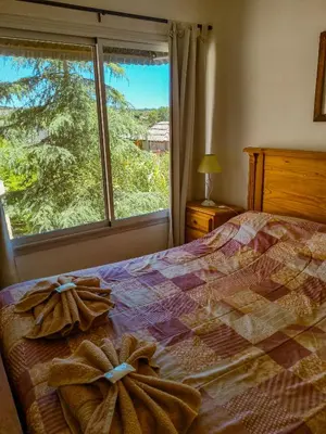 a bedroom with a bed and a large window at Cabañas Quebrada del Lobito in Villa Santa Cruz del Lago