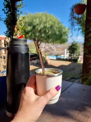 a woman holding a cup of coffee with a straw at Cabañas Quebrada del Lobito in Villa Santa Cruz del Lago