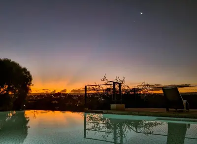 a swimming pool with a sunset in the background at Cabañas Quebrada del Lobito in Villa Santa Cruz del Lago