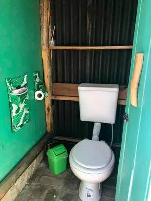a bathroom with a toilet and a green wall at Glamping Traslasierra Carpa Norte in San Javier