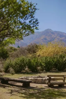two benches in a park with mountains in the background at Glamping Traslasierra Carpa Norte in San Javier