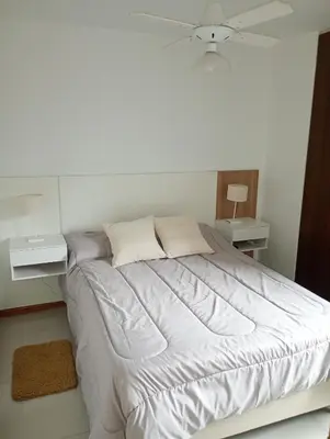 a white bedroom with a bed and two night stands at Sueños in Villa Carlos Paz