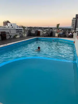 a person swimming in a swimming pool on top of a building at Sueños in Villa Carlos Paz