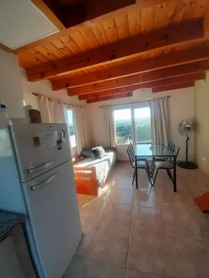 a kitchen with a refrigerator and a table in a room at Ayres Serranos in Villa Carlos Paz