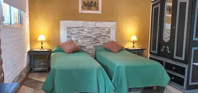 two beds with green covers in a room with two lamps at Cabañas Don Esteban in Las Chacras (La Paz)