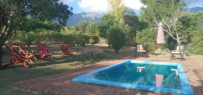 a swimming pool in a yard with chairs and an umbrella at Cabañas Don Esteban in Las Chacras (La Paz)