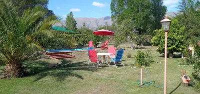 a group of chairs and a table with a red umbrella at Cabañas Don Esteban in Las Chacras (La Paz)