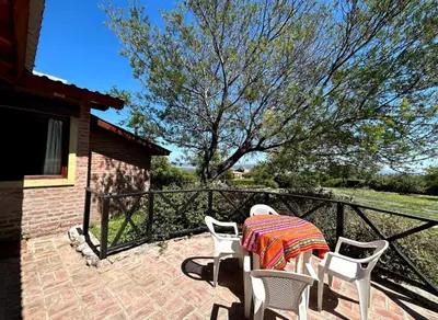 a table and chairs on a patio with a tree at La Rabona Cabañas in Las Rabonas